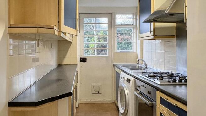 Neat galley kitchen with light wood cabinetry, ...