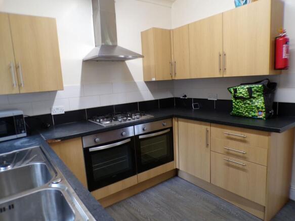 Modern kitchen featuring wooden cabinets, a sta...