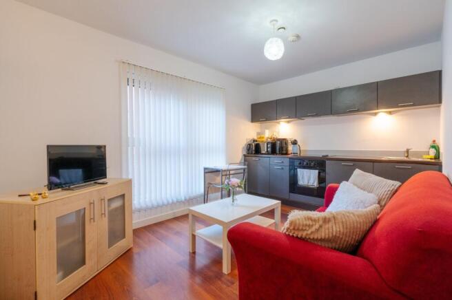 Bright open-plan living area with a red sofa, w...