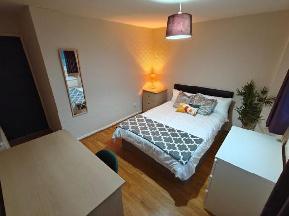 Bright furnished bedroom with desk and storage...