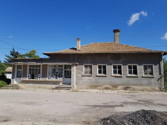 Front view of the old bakery building with tiled roof and several windows in Palamartsa village