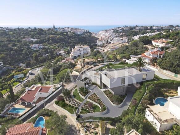 Aerial drone view of a modern luxury villa for sale in Carvoeiro Algarve with private pool landscaped gardens and distant sea views
