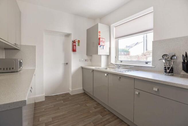 Bright, modern galley kitchen with pale grey ca...