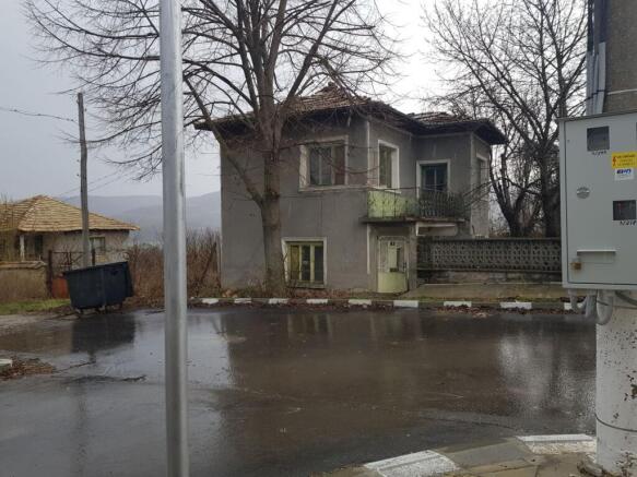 Front-facing image of the two-storey house showing balcony and surrounding leafless trees