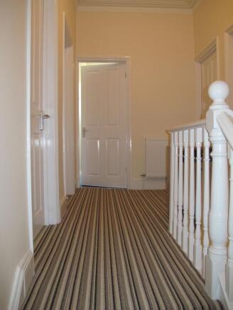 Bright upstairs hallway with striped runner car...