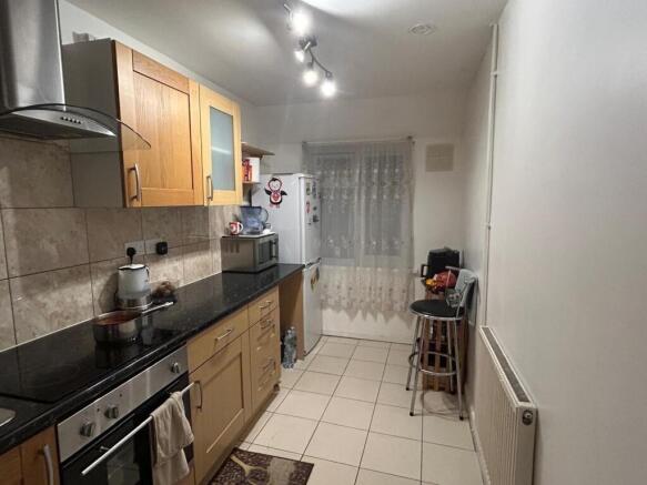 Modern galley kitchen with light wood cabinets,...