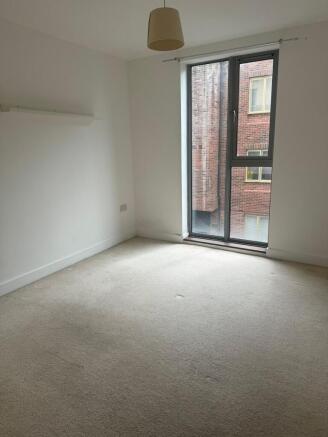 Bright room with tall window and neutral carpet...