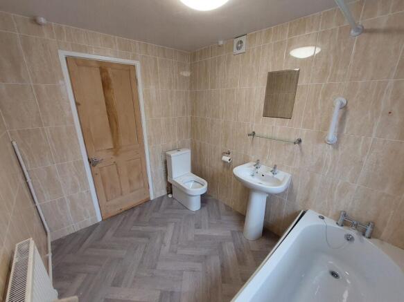 Bright, tiled bathroom with a modern white bath...