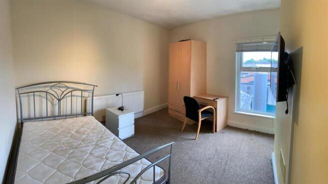Bright, simply furnished bedroom with a metal b...