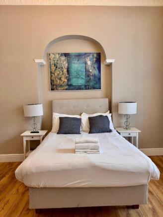 Stylish double bed with bedside lamps and artwo...