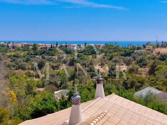 Panoramic views from the rooftop terrace of an Algarvian Quinta in Lagoa. Breathtaking countryside and distant ocean views under a clear blue sky.