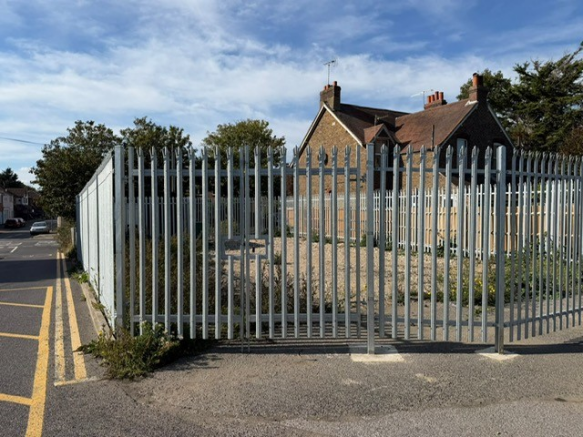 A large plot of land, with metal fencing around it.