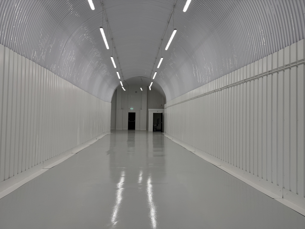 An empty arch with white lining and a WC cubicle to the back.