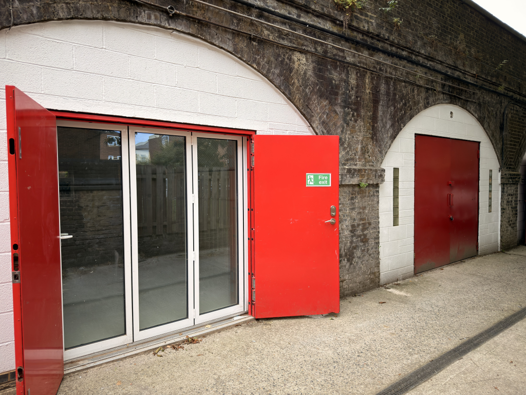 The front of an arch, with a fully glazed frontage and door allowing you to see into the arch interior.