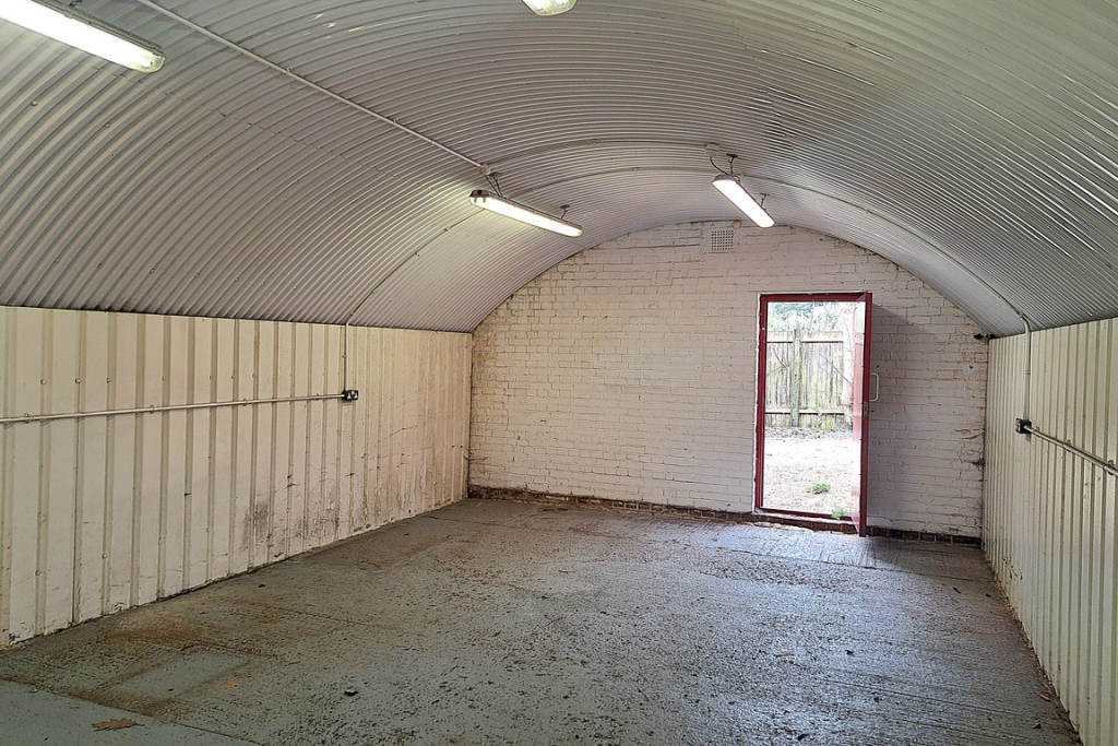 An empty arch with white lining and a fire escape door at the back.