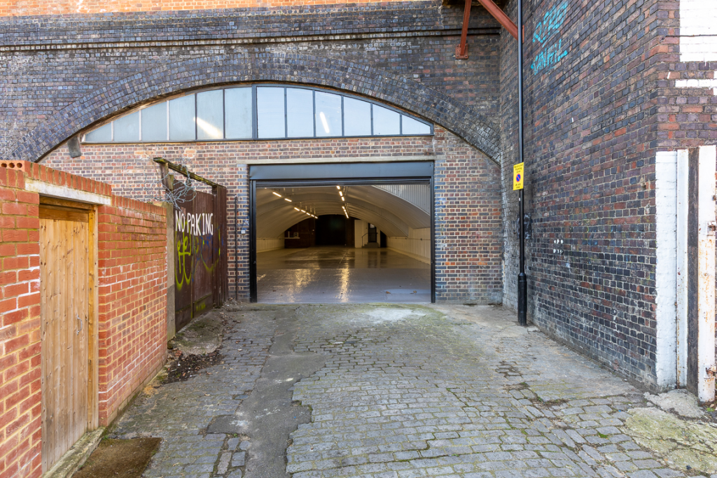 The front of an arch with an open electric roller shutter entrance big enough for vehicle access, and separate pedestrian door.