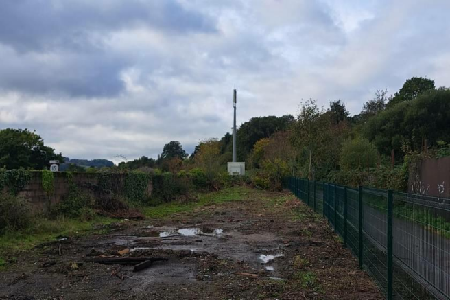 A large plot of land, with metal fencing around it.