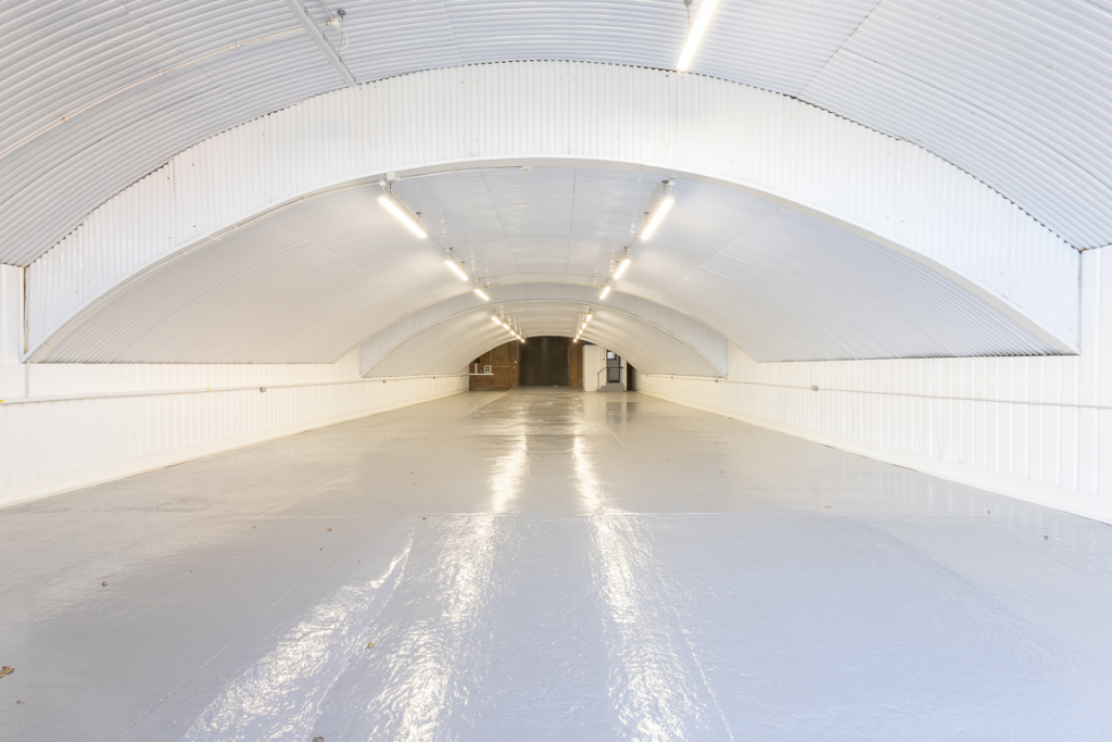 An empty arch with white lining and a WC cubicle to the back.