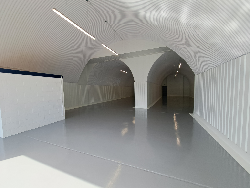 An empty arch with white lining and a WC cubicle to the front.