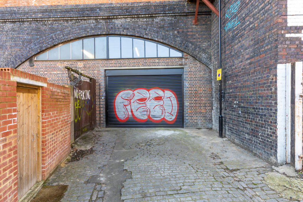 The front of an arch with a closed electric roller shutter entrance big enough for vehicle access.