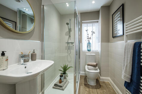 En suite with glass shower cubicle and white tiled walls