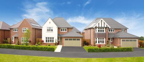 Modern detached houses with front gardens and driveways in a suburban neighbourhood, under a clear b