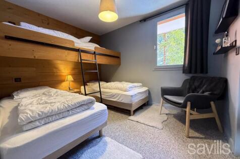 This image shows a cozy bedroom with three beds, i