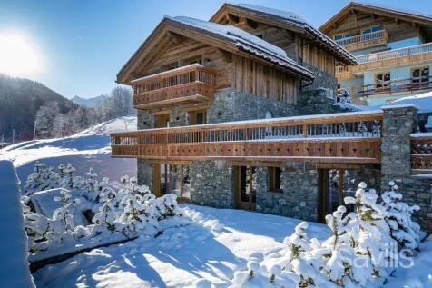 A wooden chalet covered in snow, surrounded by a s