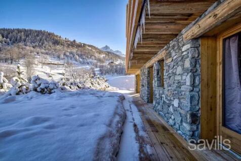 A rustic stone chalet surrounded by snow, set in a