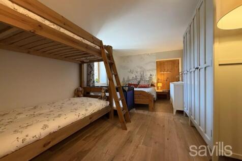 A cozy bedroom with wooden bunk beds, a single bed
