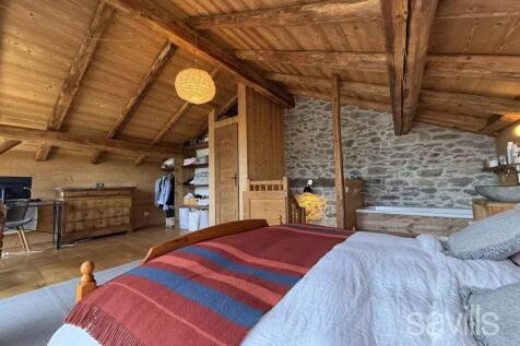 This cozy attic bedroom features a wooden ceiling 