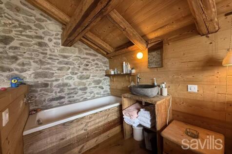 A rustic bathroom featuring a stone wall, wooden b