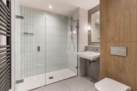 Step into luxury with this sleek bathroom featuring a modern glass shower and elegant finishes.