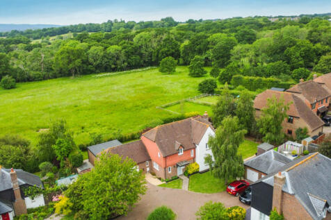Elevated view of the house with field and woodland behind