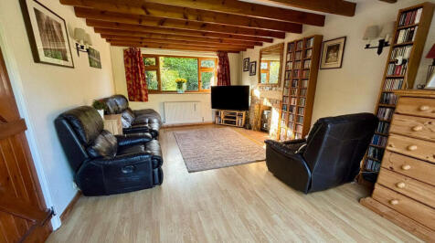 Living room with woodburner and double doors opening onto the rear garden