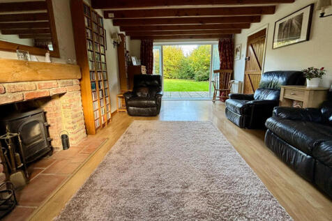 Living room with woodburner and double doors opening onto the rear garden