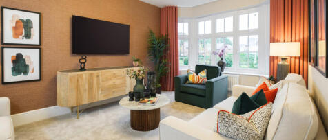 Modern living room with white sofa, green armchair, wall-mounted TV, colourful cushions, and large b