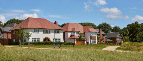 A row of modern detached houses with red tiled roofs and white and brick exteriors, set against a br