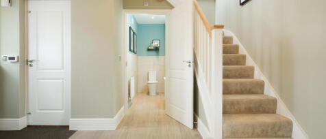 Interior view of a modern home with a staircase, doorways, and a small bathroom at the end, decorate