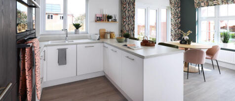 Modern kitchen with white cabinets, a central island, large windows, and a dining area with pink and