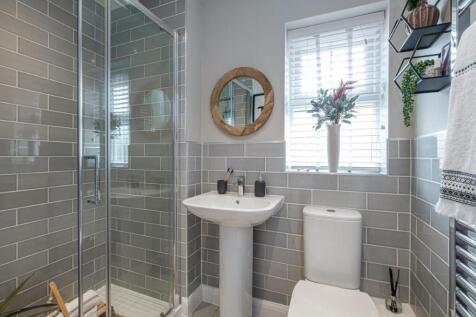 Photo of a tiled bathroom with a bath, sink, toilet and window