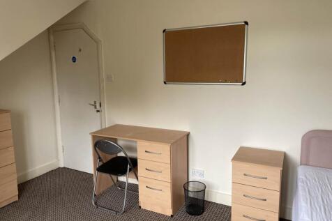 Neat furnished bedroom with a desk, chest of dr...