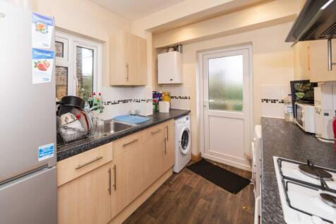 Bright modern kitchen with light wood cabinets,...