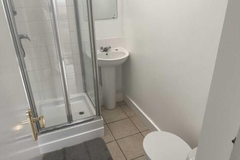 Clean, neutral bathroom with a corner shower en...