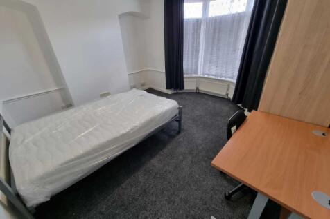 Bright, simple bedroom with a single bed beside...