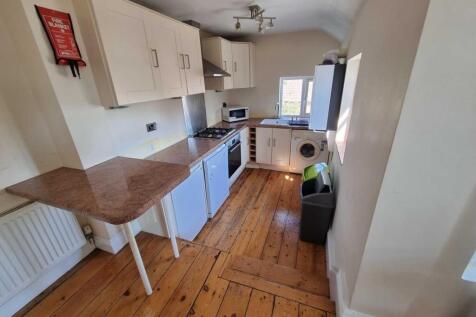 Bright galley-style kitchen with wooden floors,...