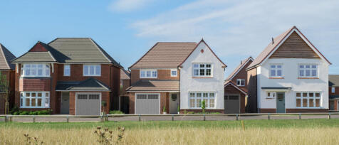 A row of three modern detached houses with varied white and brick facades, set against a blue sky wi