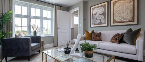 Bright living room with large window, white sofa, decorative cushions, coffee table, and wall art in