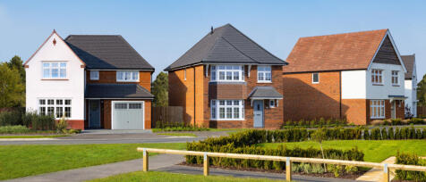 Modern multi-storey residential building with brick and paneling exterior, balconies, and landscaped