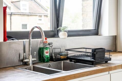 This modern kitchen features sleek countertops ...